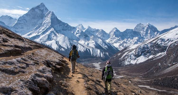 Hikers walking on a pathway with Himalayan mountains in the background.