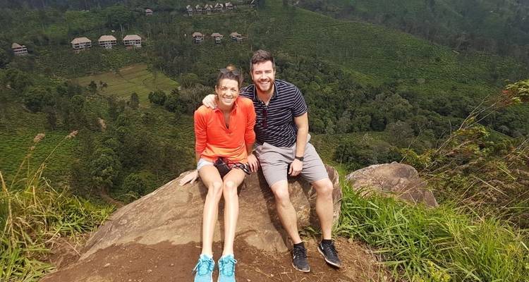 Un couple assis sur un rocher surplombant le paysage.