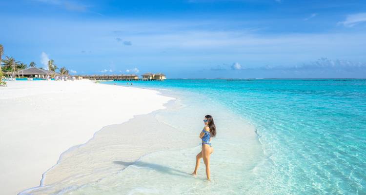 Femme profitant d'une journée ensoleillée sur une plage de sable blanc immaculée.