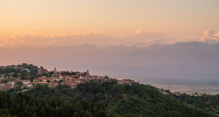 Scenic view of a small town and mountains at sunset.