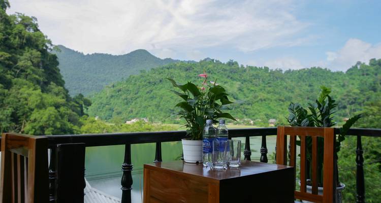 Outdoor balcony set with water bottles and plants overlooking green hills and a lake