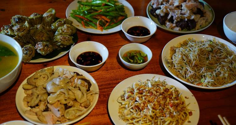 Wooden table set with multiple Vietnamese dishes, sauces, and vegetables ready to eat.