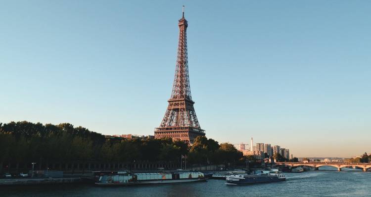 Tour Eiffel au bord de la rivière avec des bateaux amarrés.