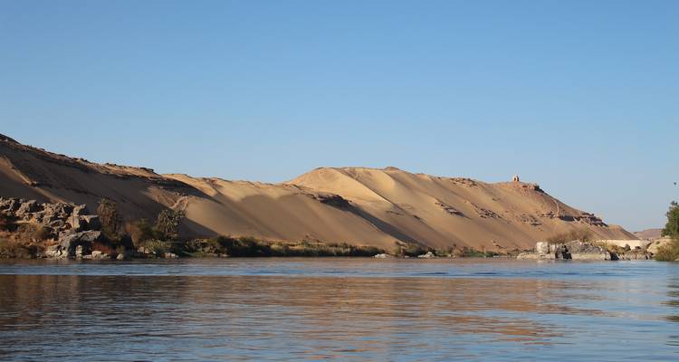 A river with desert dunes in the background.