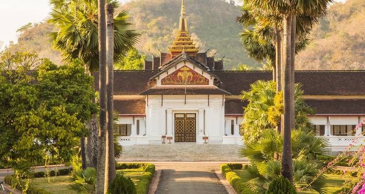 Elegant Royal Palace Museum of Luang Prabang framed by tall palm trees and manicured gardens.