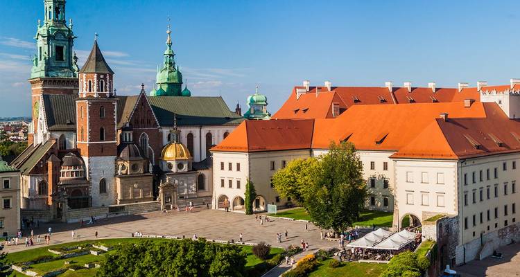 Complexe du château de Wawel avec des toits en tuiles rouges, des tours de cathédrale et une cour verdoyante dominant Cracovie
