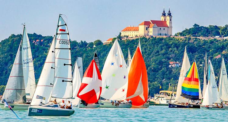 Zeilboten met kleurrijke zeilen racen voor een pittoresk stadje.