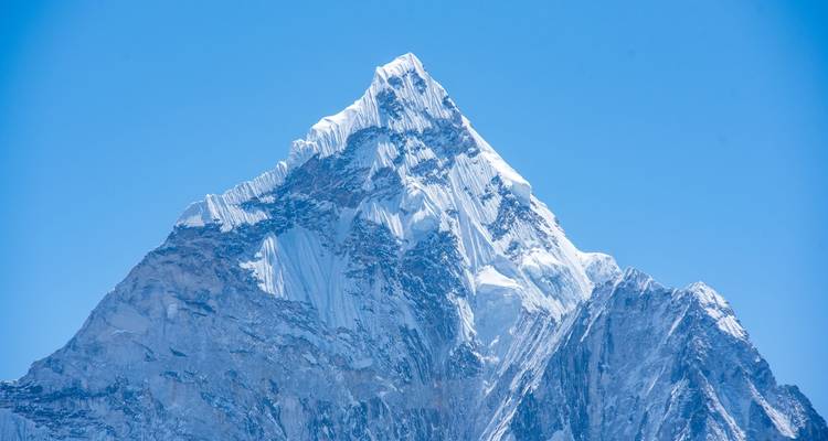 Close-up van een indrukwekkende besneeuwde Himalaya-top tegen een dieperblauwe hemel