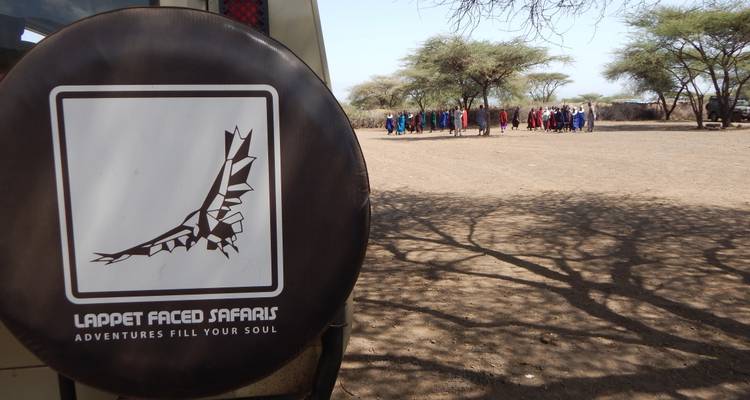 Voertuig met een safari-logo en mensen in de verte.