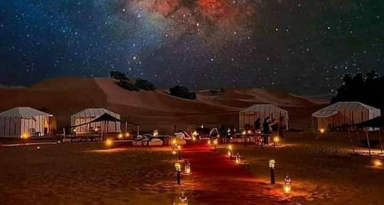 Luxe woestijnkamp onder een sterrenhemel met verlichte paden.