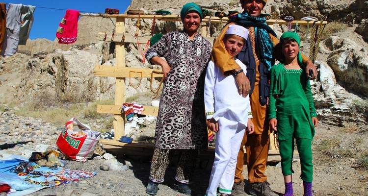 Familia posando con ropa tradicional frente a un puesto improvisado.