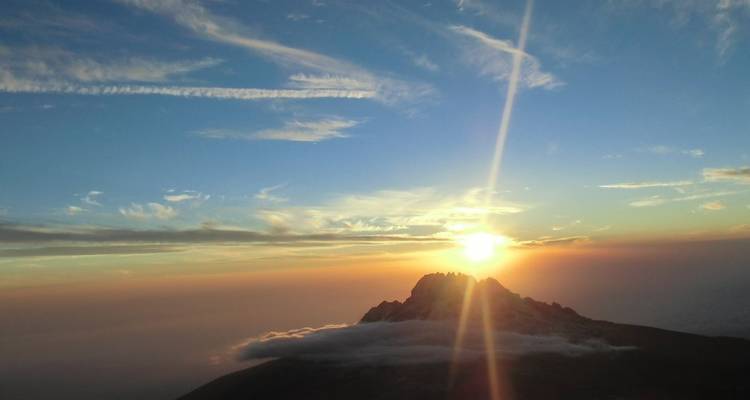 Lever de soleil sur un sommet de montagne avec un ciel dramatique.