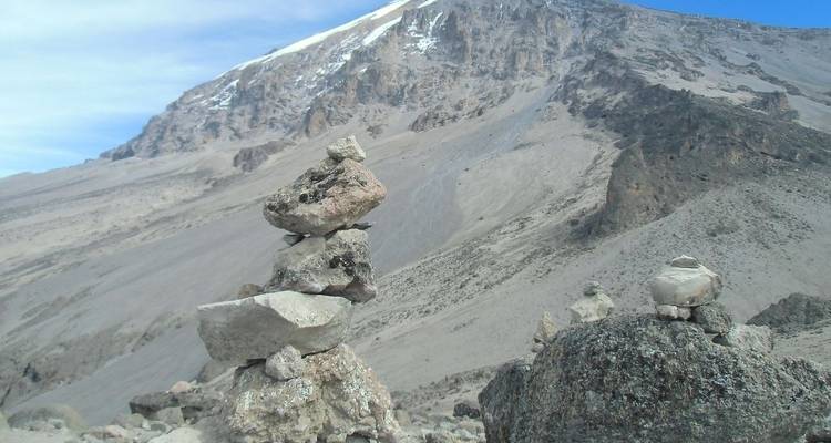 Cairns de pierres sur un versant de montagne avec des plaques de neige.