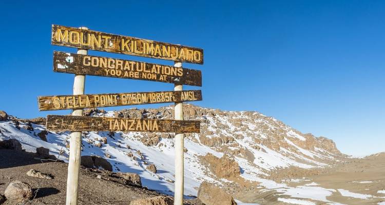 Panneau indicateur à Stella Point sur le mont Kilimandjaro avec un paysage montagneux enneigé en arrière-plan.