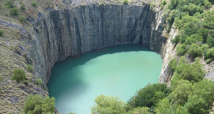 Vertical rock formation surrounding a pool of water.