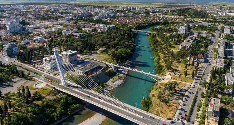 Stadtansicht mit einem Fluss und einer Hängebrücke.