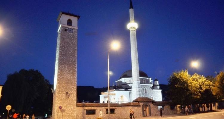 Nachtansicht einer Moschee und eines Uhturms.