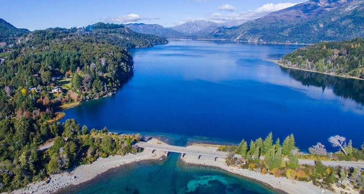Vista panorámica de un gran lago con bosques y montañas circundantes.