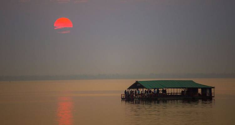 Atardecer sobre un lago sereno con una balsa flotante.