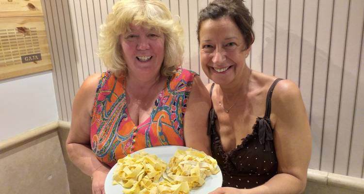Zwei Frauen präsentieren einen Teller mit Nudeln.