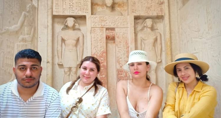 Group of people posing in front of ancient sculptures.
