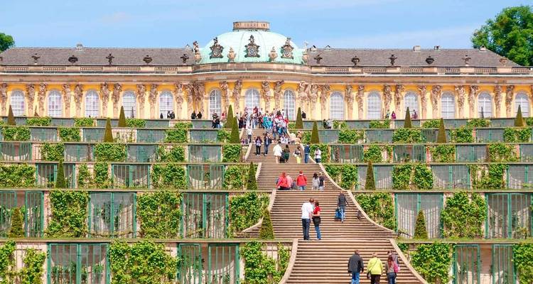 Bezoekers die de grootse terrasvormige wijngaarden en trappen naar Paleis Sanssouci beklimmen op een zonnige dag.