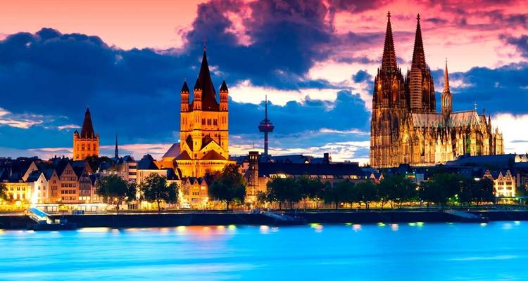 Dramatische schemering skyline van Keulen met de verlichte dom en de Grote Sint-Martinuskerk weerkaatsend op de Rijn.
