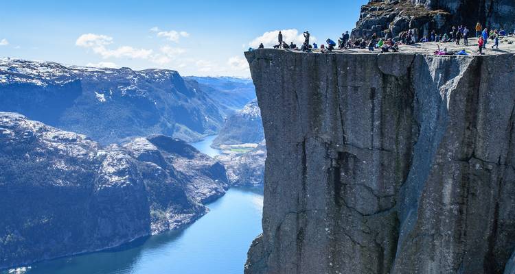 Los excursionistas descansan en el dramático acantilado de Preikestolen muy por encima del Lysefjord con vistas panorámicas de las montañas.