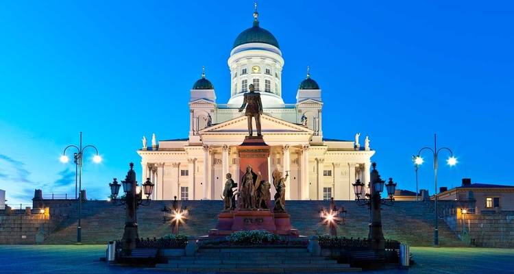 Striking neoclassical Helsinki Cathedral illuminated against deep blue evening sky.