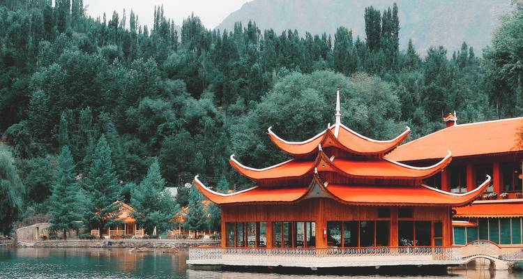 Traditioneel gebouw in pagodestijl aan een meer omringd door weelderig groen.