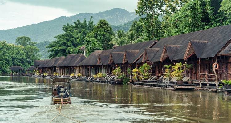 Floating houses along a river surrounded by lush mountains.