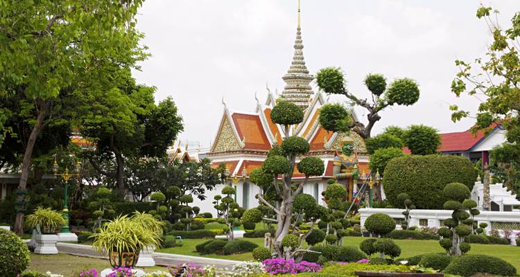 Beautifully landscaped temple gardens with trimmed trees and colorful flowers.