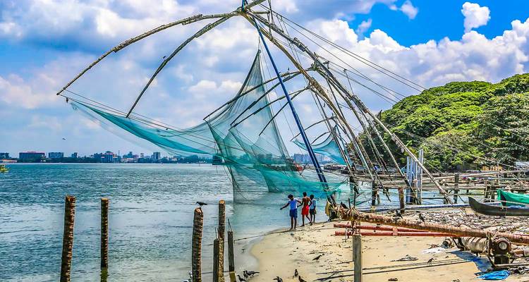Filets de pêche chinois avec des pêcheurs le long du rivage.