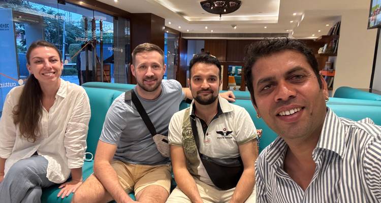 Four people sitting on a blue couch indoors.