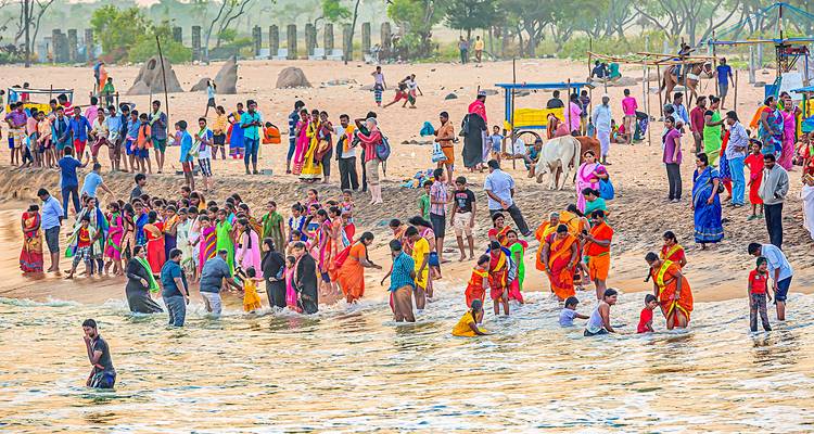A crowded beach with people and stalls, possibly during a festival.