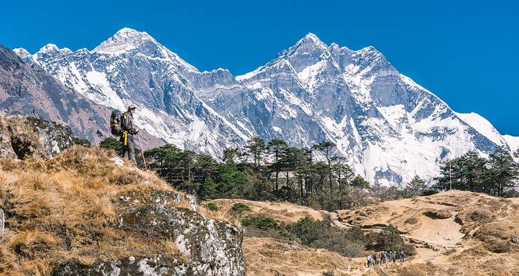 Een wandelaar met besneeuwde bergen op de achtergrond.