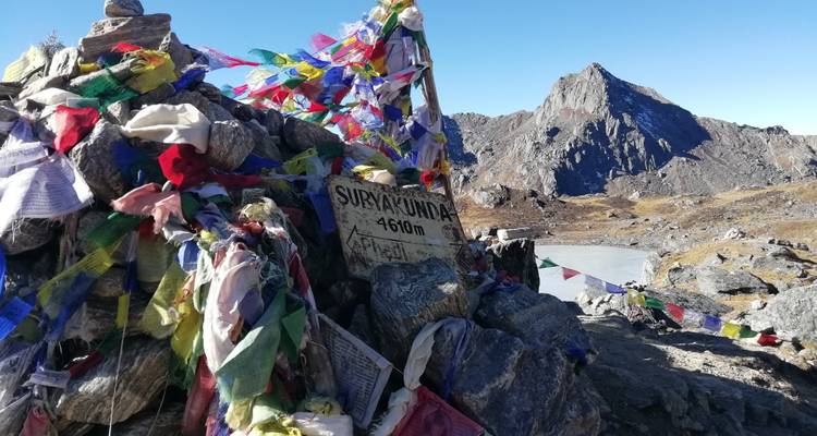 Felsenmonument mit bunten Fahnen und bergiger Kulisse.