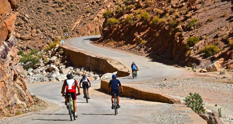 Cyclistes sur une route de montagne sinueuse avec un terrain rocheux.