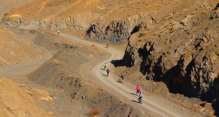 Des gens faisant du vélo sur une route désertique montagneuse.