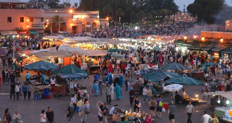 Marché du soir animé avec des étals colorés et des foules de gens.