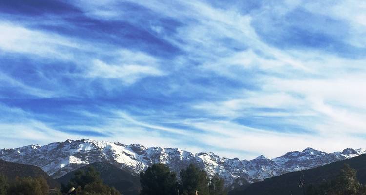 Chaîne de montagnes enneigée sous un ciel bleu avec des nuages épars.