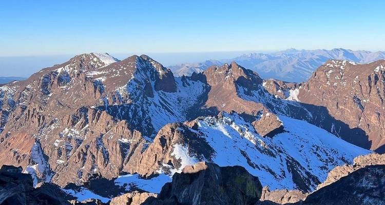Mountainous landscape with snow-capped peaks under a clear sky.