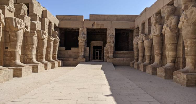 Pad die leidt naar de ingang van een oude Egyptische tempel met beelden.