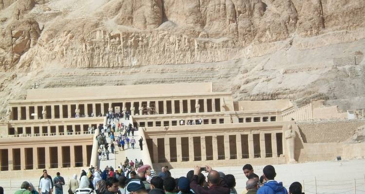 Groepen toeristen die een oude tempelstructuur bezoeken tegen een klif.