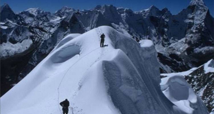 Bergsteiger, die einen verschneiten Grat überqueren.