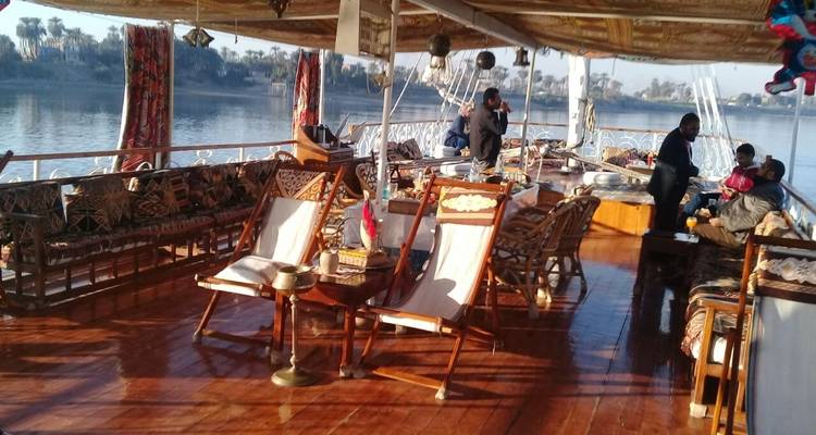 Mensen op een traditionele houten boot op een rivier, met een ingewikkeld ontworpen dek.