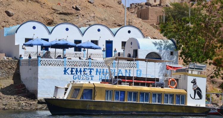Gastenverblijf aan de rivier met een boot ervoor, voorzien van decoratieve Egyptische kunst.