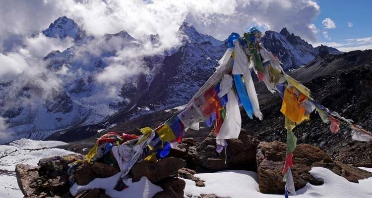 Gebetsflaggen in einer Berglandschaft mit schneebedeckten Gipfeln.