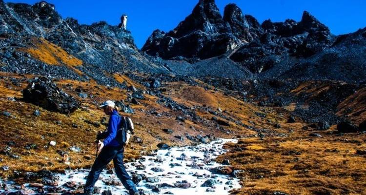 Person, die auf felsigem Gelände mit Bergen im Hintergrund geht.