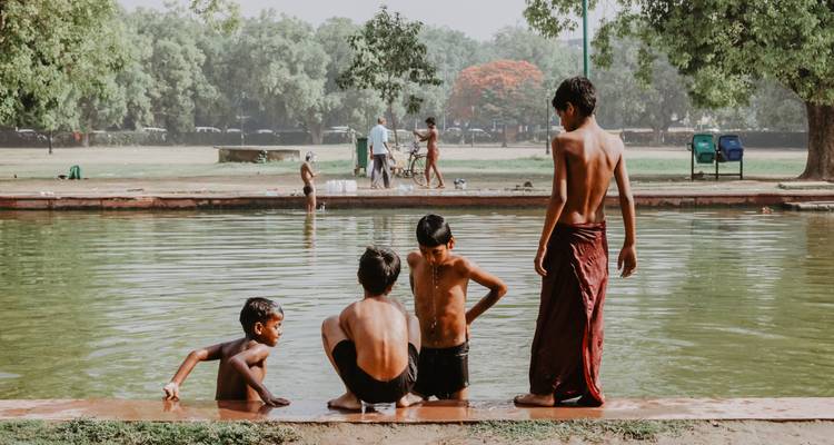 Des enfants jouent près d'un point d'eau entouré d'un jardin.